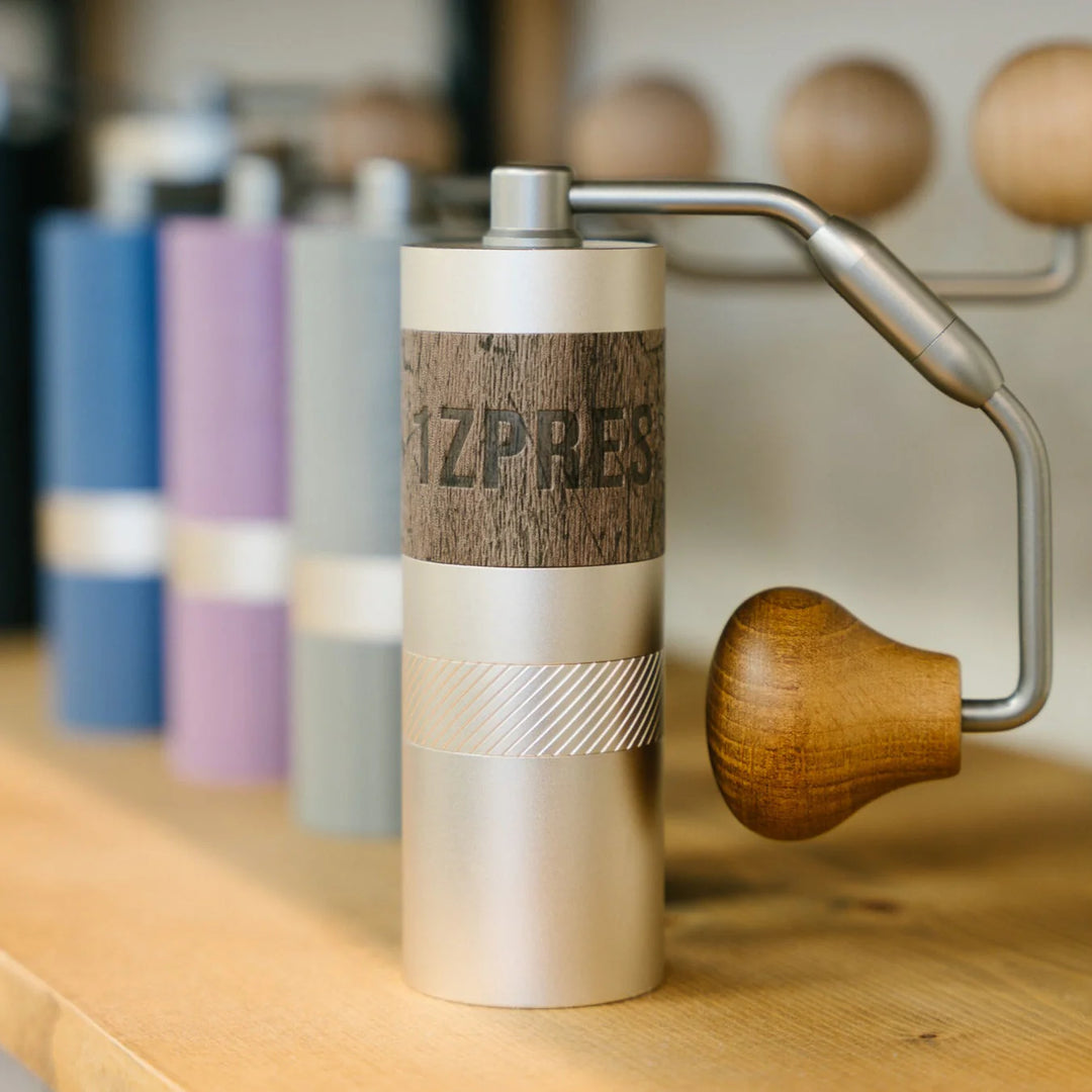 1Zpresso Q manual coffee grinder with foldable handle and dark wood knob.